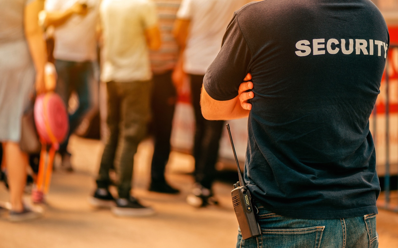 Sicherheitsbeamter überwacht Menschenmenge mit Funkgerät