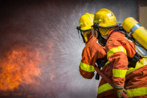 Feuerwehrleute löschen Flammen mit Wasserschlauch